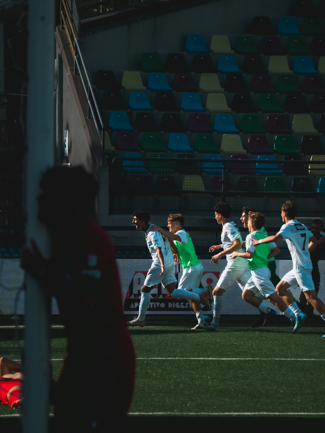 Giocatori di calcio in maglia bianca e verde festeggiano su un campo.