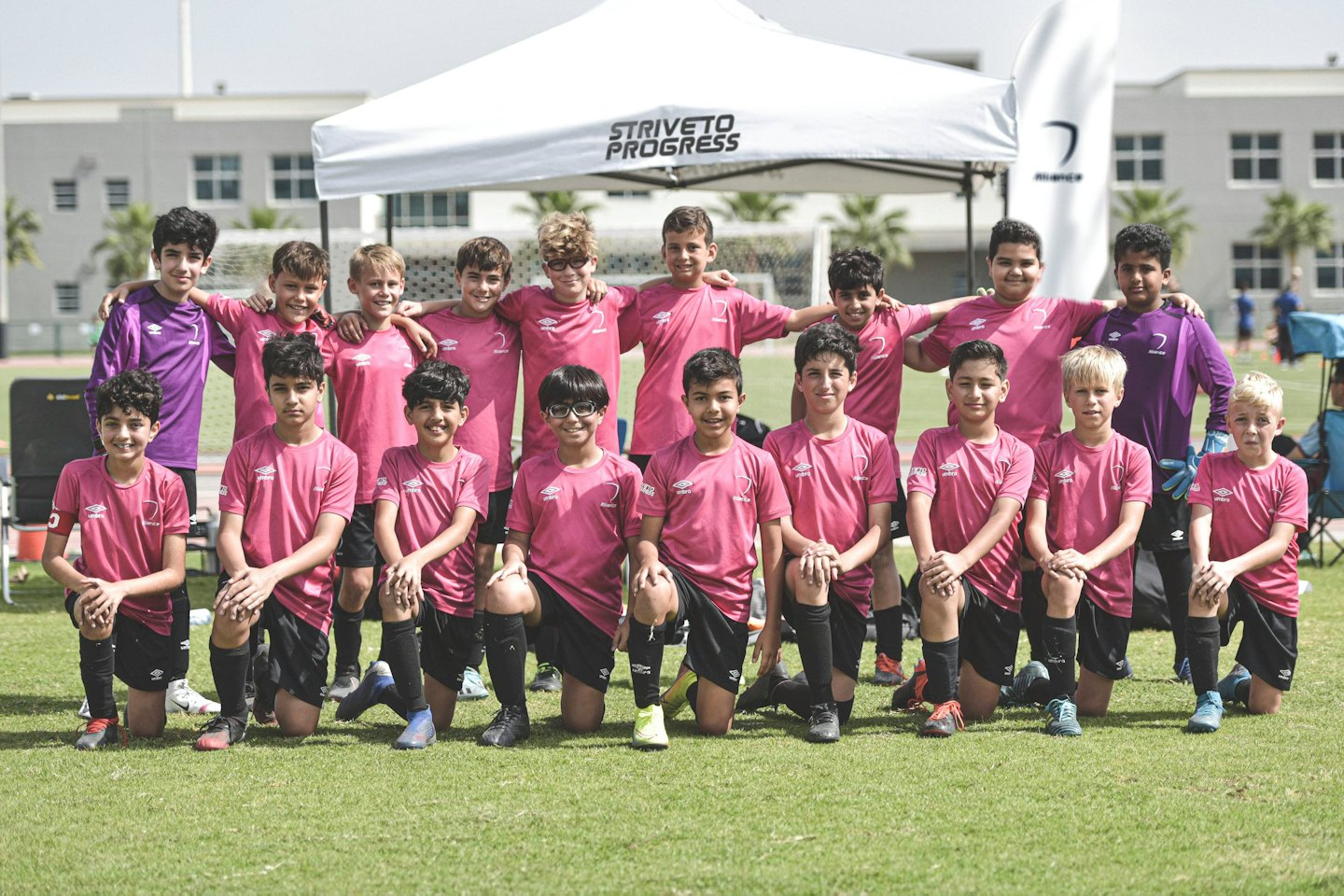 Ragazzi in maglia da calcio posano su un campo verde.